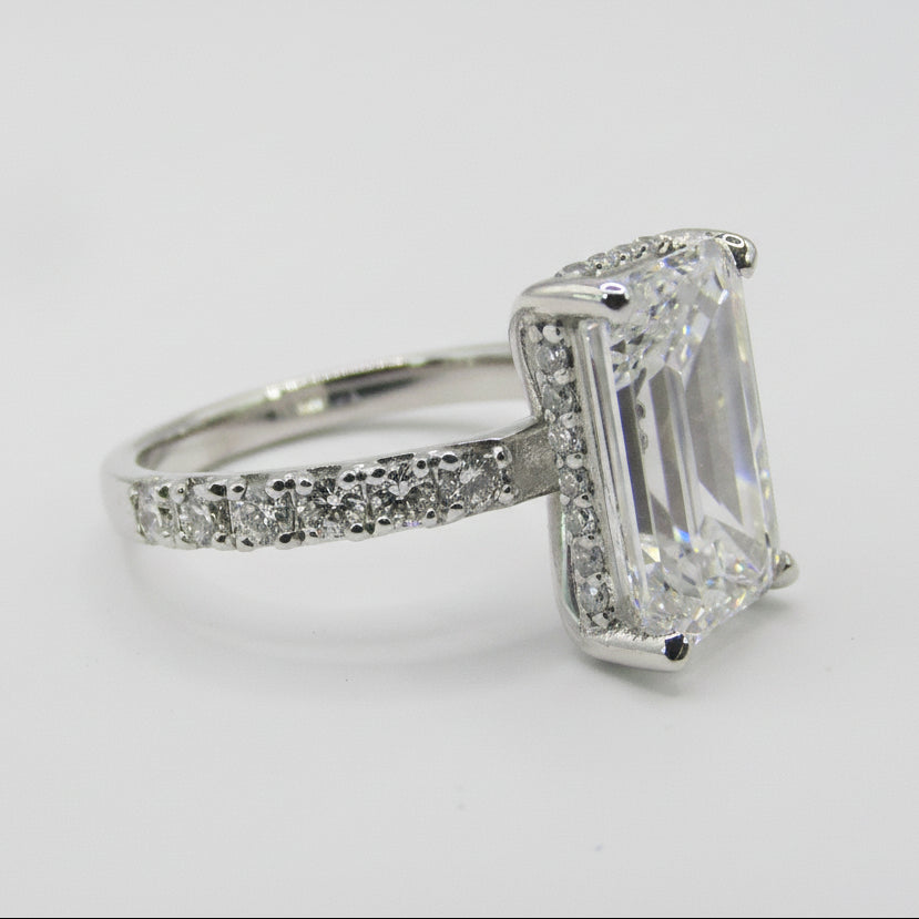 Side view of emerald cut engagement ring showing pavé diamond band